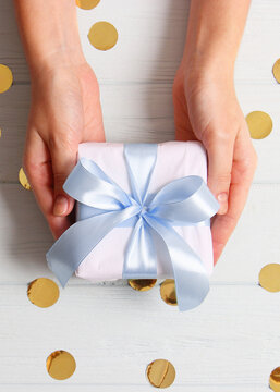 gift in female hands on a colored background with confetti top view.. Vertical photo format