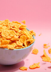 Delicious cornflakes in a plate against colored background.. Vertical photo format
