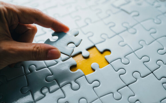 Hand placing the final puzzle piece to complete a solution, symbolizing business strategy, problem-solving, and teamwork. - Powered by Adobe