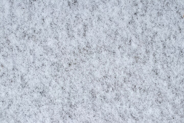 Snow texture on ground, natural winter background with thin layer of snow, abstract cold pattern for use in design as background or decorative seasonal template