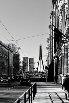 Fototapeta A black-and-white, realistic photograph of a cityscape featuring a bridge. The image emphasizes architectural details, lines, and contrasts, creating a timeless and dramatic urban atmosphere.