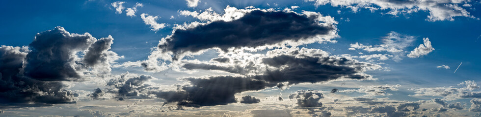 Panoramafoto des dramatischen, kontrastreichen Wolkenhimmels mit durch die Wolken scheinenden...