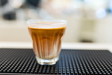 A glass of espresso shot over cold fresh milk create gradient layer called dirty coffee on counter