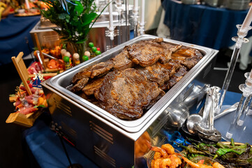 Grilled meats at the banquet. Tender grilled meats are beautifully arranged at an upscale banquet,...