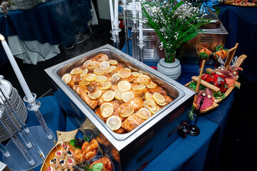 Lemon fish dish at event. A buffet showcases fish with lemon slices, elegantly decorated for an evening gathering.