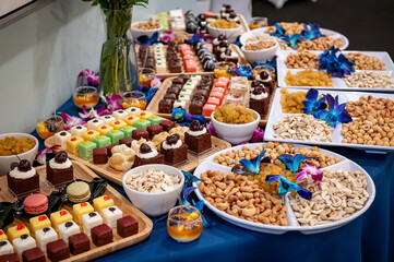 Event dessert table with treats. A vibrant array of cakes, pastries, and snacks decorated with...