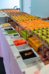 Colorful sushi display at a buffet event. Colorful sushi rolls are displayed on a long table at a...