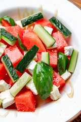 Refreshing watermelon and cucumber salad. A vibrant salad featuring juicy watermelon, crisp cucumber, and fresh basil drizzled with olive oil, ideal for summer.