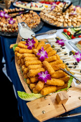Crispy snacks for the party. A colorful platter displays crispy snacks garnished with flowers, attracting guests at a lively event.
