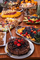 Colorful festive dessert table. A vibrant array of sweets and fruits displayed on a wooden table for a celebration, featuring cakes and fresh berries.