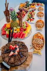 Fresh fruits and snacks on display. A colorful display of fruits and snacks is elegantly arranged on the table for guests to enjoy.