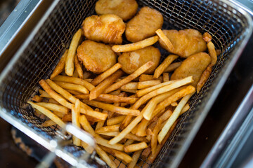 Crispy chicken nuggets with french fries after cooking. Close up
