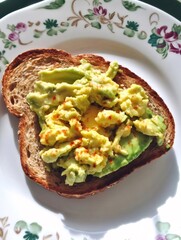 Whole Wheat Toast Topped with Avocado Slices and Red Pepper Flakes on Floral Plate