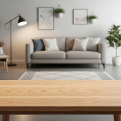 Empty light beige wooden table in front of a blurred modern living room scene with gray sofa, neutral wall colors, and art pieces.