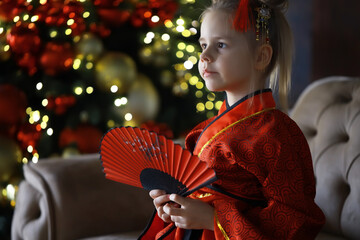 Child in Traditional Kimono Holding Fan with Festive Background and Bokeh Lights