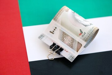 United Arab Emirates dirham currency money bills lies on flag. The concept of business and...