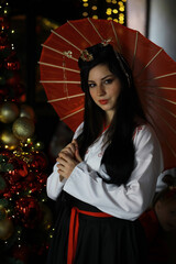 Woman in Traditional Attire Holding Parasol Near Christmas Decorations