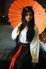 Traditional Asian Attire with Orange Parasol - Elegant Woman Posing in Cultural Dress
