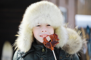 Child Enjoying Winter Candy Outdoors in Warm Fur Hat