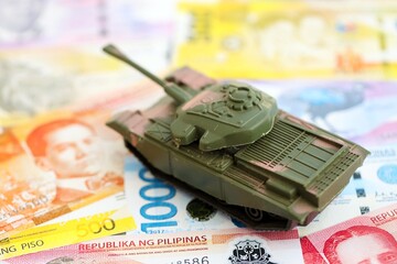 Philippines peso currency money bills and toy tank. The concept of army funds and weapons sales