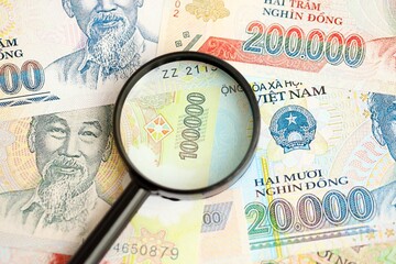 Vietnamese dong currency money bills and magnifying glass. The concept of financial monitoring and taxation