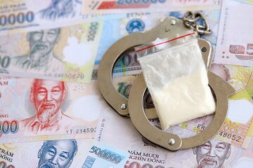 Vietnamese dong currency money bills and cocaine pack with handcuffs. The concept of drug crimes