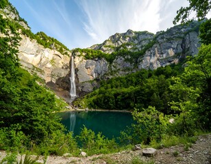 Majestic waterfall cascading into a tranquil alpine lake, surrounded by lush greenery and mountains