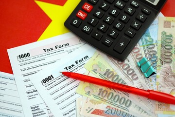 Vietnamese dong money bills and calculator with tax form on flag. Taxation and accounting concept