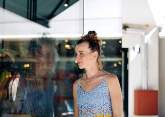 Caucasian female young adult reflecting in store window wearing blue top