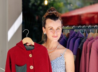 Female vendor displaying red jacket at outdoor clothing market