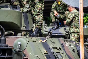 Soldiers boarding armored vehicle, Military climbing onto tank, Armed forces entering armored troop...