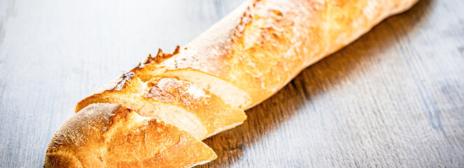 still life with French fresh bread baguettes with poolish on a wooden cutting board and wheat,...