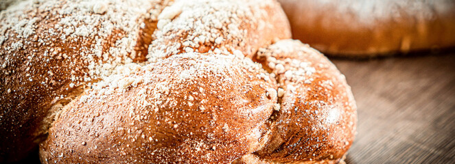 Braided buns bread decorated with sugar above on a wooden table background