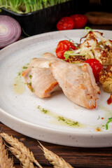 Juicy baked turkey fillet served with roasted cauliflower, cherry tomatoes and herbs on white plate in rustic food styling