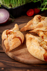 Freshly baked puff pastry pies with savory filling served on wooden board traditional rustic style food photography
