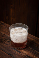 Classic white russian cocktail with vodka, coffee liqueur, ice and cream served in lowball glass on rustic wooden table