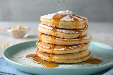Stack of delicious pancakes drizzled with honey and sprinkled with powdered sugar on a blue plate