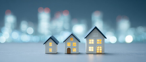 Rising Property Market: Miniature houses illuminate against a blurred cityscape at twilight, symbolizing the upward trajectory of the property market and the growth of homeownership.