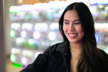 Happy young woman playing arcade video games indoors