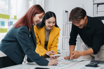 Asian Business Team Collaboration in Modern Office Space Analyzing Data Using Calculator and Charts for Financial Growth Planning and Success