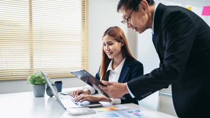 A man and a woman are working together on a laptop