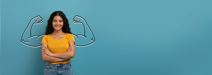 A confident Indian woman stands against a blue background, smiling and flexing her biceps. Her...