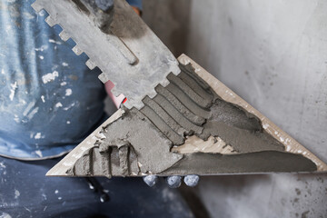 Closeup of the hands of a tiler during renovation - laying ceramic tiles on the floor and walls