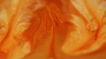 Enamel liquid. Sparkling texture. Defocused yellow orange color paint flowing in water stains spilling on abstract acrylic background.
