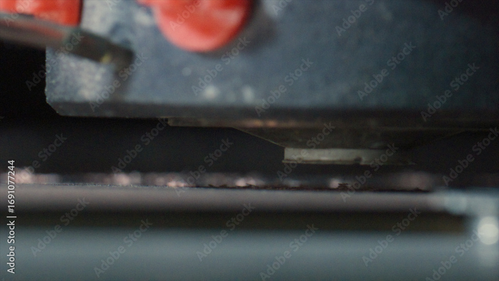 Poster close up of a 3d printer extruder depositing molten plastic filament onto a build platform, creating