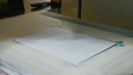 White sheet of paper material being precisely laser cut by a modern automated machine, creating a...
