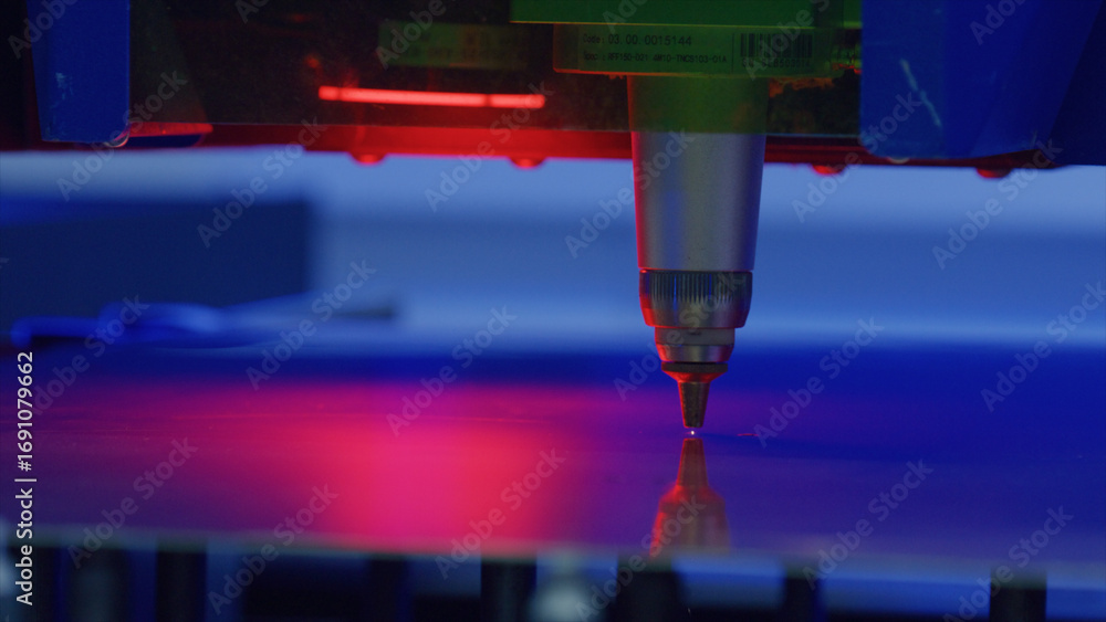 Poster laser engraving machine is engraving a metal surface, emitting a red light, creating a precise and i