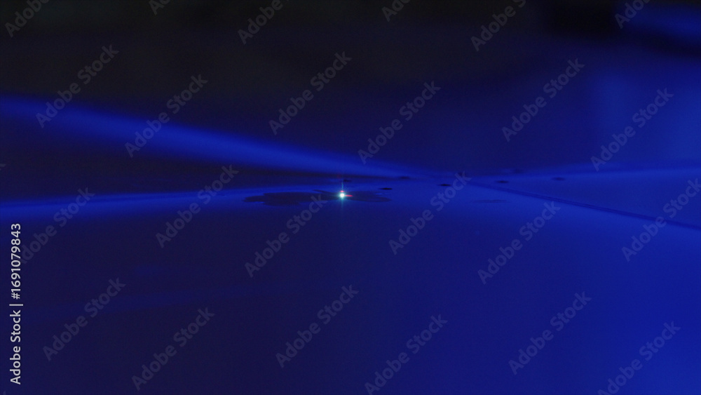 Poster powerful laser beam creating a bright light spot on a smooth blue surface, highlighting concentrated