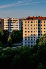 Naklejka premium 日中の穏やかな光の中の緑の木々のあるクリーム色の建築物