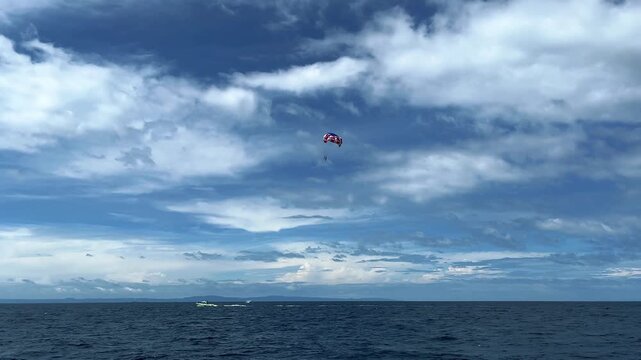 Two people fly on a parachute over a sky-blue sea on two domes towed by a boat. parasailing